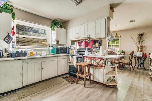 kitchen featuring pendant lighting, white cabinets, light hardwood / wood-style flooring, black / electric stove, and custom range hood