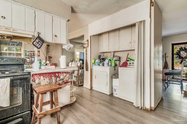 kitchen with black range with electric stovetop, white cabinetry, light hardwood / wood-style flooring, and washing machine and dryer