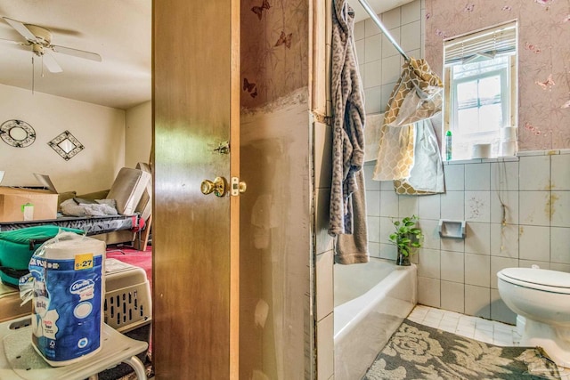 bathroom featuring shower / bath combination with curtain, tile patterned floors, ceiling fan, tile walls, and toilet