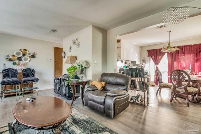 living room with light wood-type flooring and an inviting chandelier