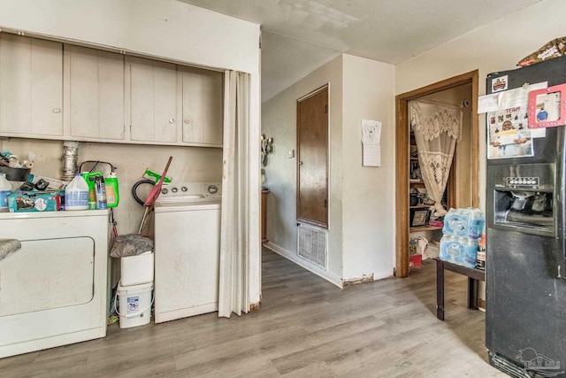 washroom with cabinets, separate washer and dryer, and light hardwood / wood-style floors