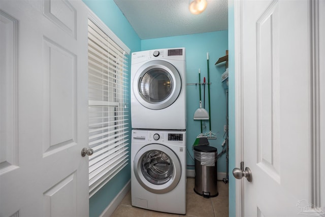 laundry room featuring light tile patterned floors, a textured ceiling, and stacked washing maching and dryer