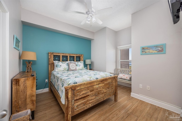 bedroom featuring ceiling fan, light hardwood / wood-style floors, and a textured ceiling