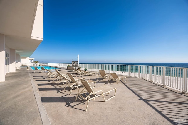 view of patio / terrace featuring a view of the beach, a water view, and a community pool