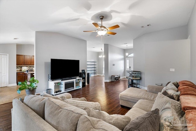 living room with vaulted ceiling, dark wood-type flooring, and ceiling fan with notable chandelier