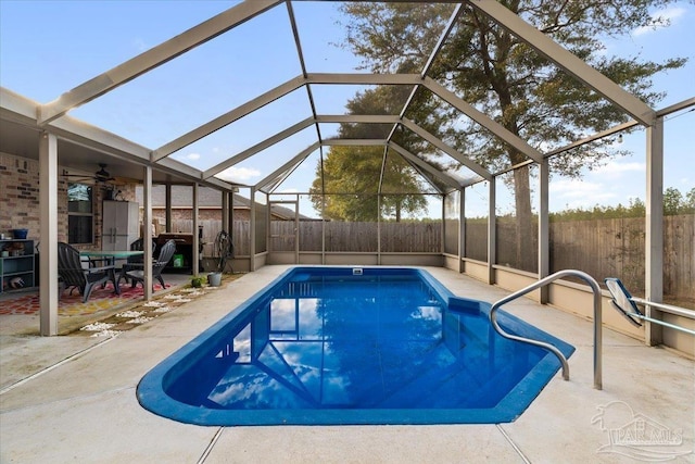 view of swimming pool featuring a patio, ceiling fan, and glass enclosure