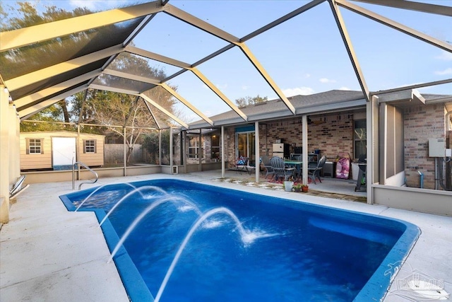 view of swimming pool with pool water feature, a storage unit, a lanai, and a patio area