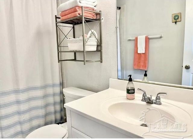 bathroom featuring toilet, walk in shower, and vanity