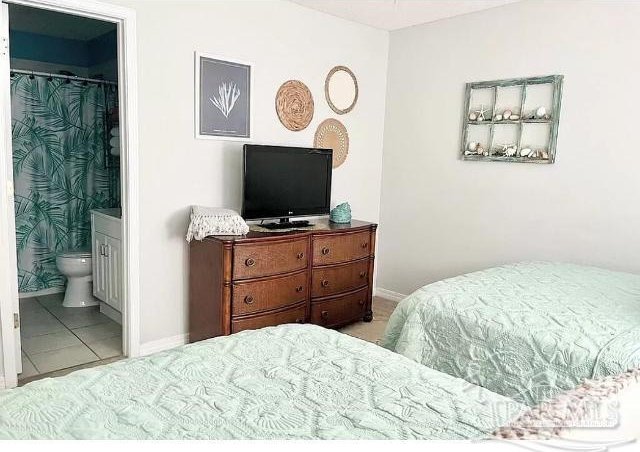 tiled bedroom with a walk in closet and ensuite bathroom