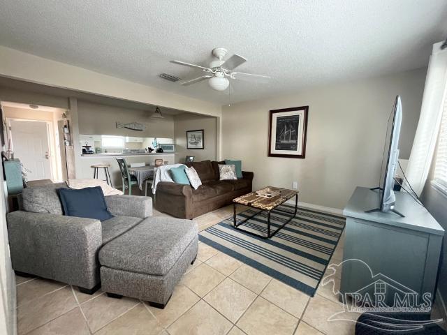 tiled living room featuring a textured ceiling and ceiling fan