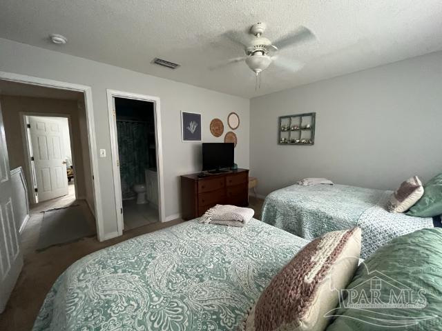 bedroom featuring ceiling fan, carpet, connected bathroom, and a textured ceiling