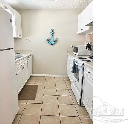 kitchen featuring white cabinetry, light tile patterned floors, and white appliances