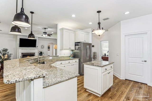 kitchen featuring a sink, arched walkways, freestanding refrigerator, a peninsula, and ceiling fan