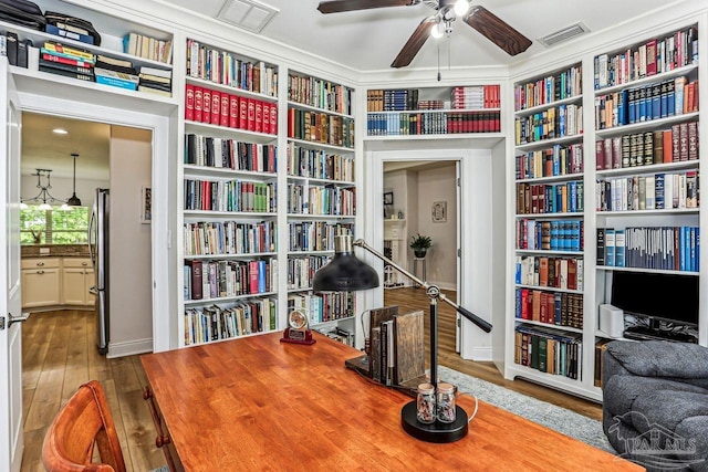 living area featuring ceiling fan, visible vents, and bookshelves