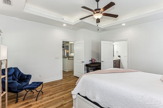 bedroom with recessed lighting, a raised ceiling, hardwood / wood-style floors, and visible vents