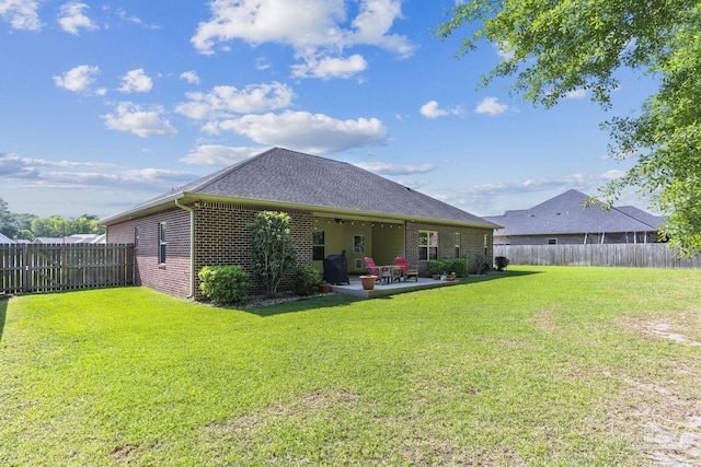 back of property with a fenced backyard, a yard, ceiling fan, a patio, and brick siding