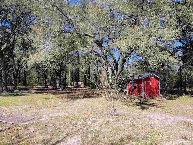 5927 Mitchell Ln, Pensacola, FL 32526 - view of yard featuring an outdoor structure, a wooded view, and a shed