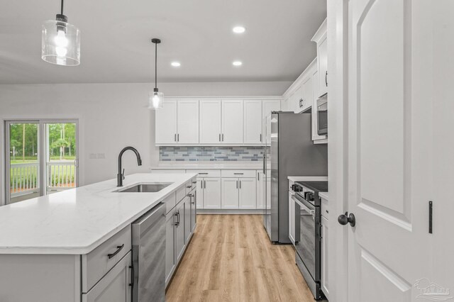 1192 Adrian Way, Milton, FL 32583 - kitchen featuring appliances with stainless steel finishes, a sink, tasteful backsplash, white cabinets, and a center island with sink