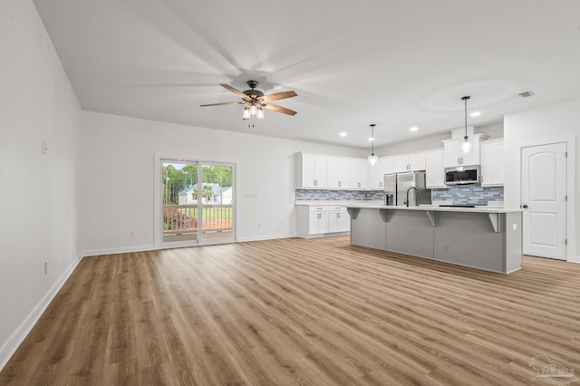 1192 Adrian Way, Milton, FL 32583 - kitchen with stainless steel appliances, a breakfast bar area, backsplash, light wood-type flooring, and light countertops