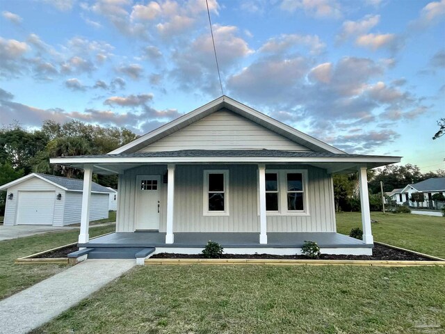 view of front facade with a garage, an outbuilding, a porch, and a front yard