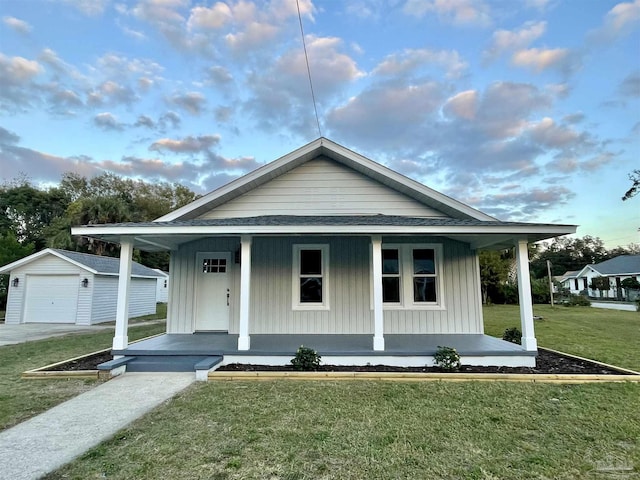 view of front of house featuring an outbuilding, a garage, a front lawn, and covered porch