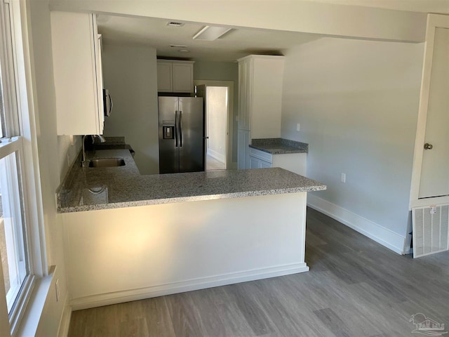 kitchen featuring appliances with stainless steel finishes, white cabinetry, wood-type flooring, and kitchen peninsula