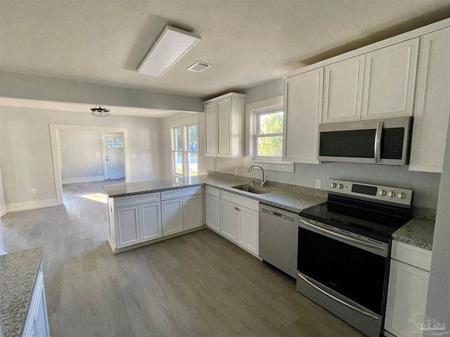 kitchen featuring stainless steel appliances, white cabinets, sink, kitchen peninsula, and light hardwood / wood-style floors