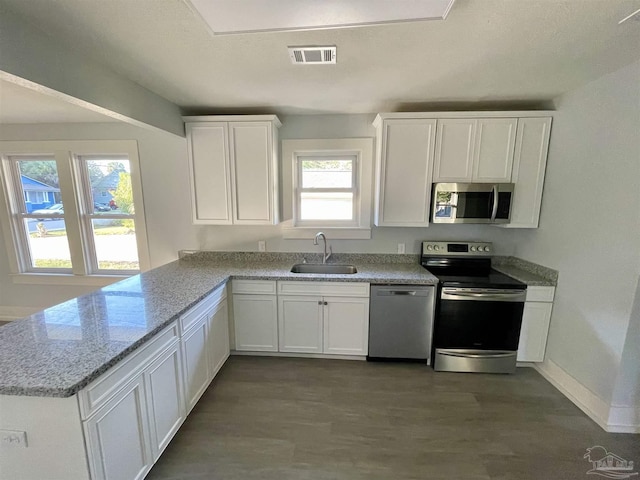 kitchen with dark wood-type flooring, sink, light stone counters, appliances with stainless steel finishes, and white cabinets