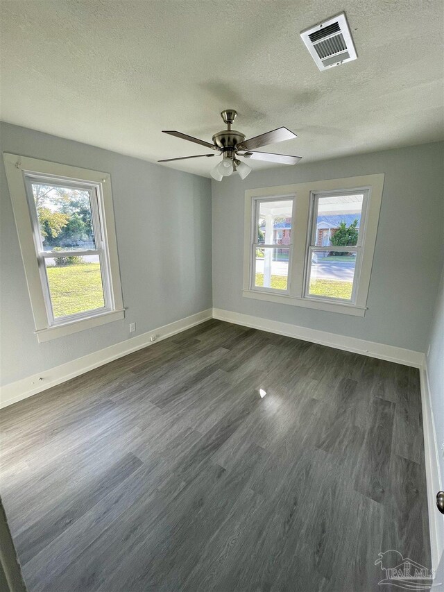 spare room featuring dark wood-type flooring, a textured ceiling, and ceiling fan