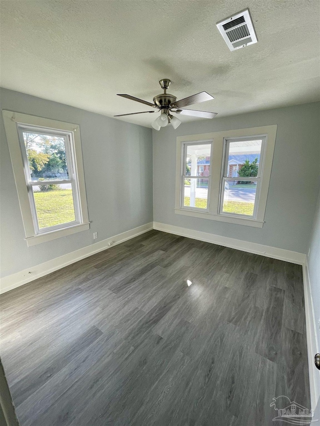 spare room featuring ceiling fan, dark hardwood / wood-style flooring, a textured ceiling, and a wealth of natural light