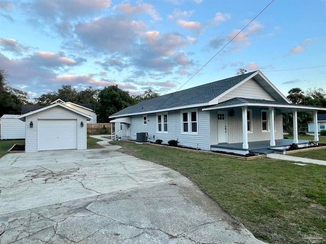 view of front facade featuring a lawn, an outbuilding, a porch, central AC, and a garage