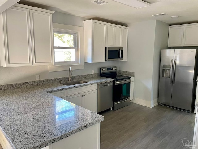 kitchen featuring white cabinets, light stone countertops, appliances with stainless steel finishes, and sink