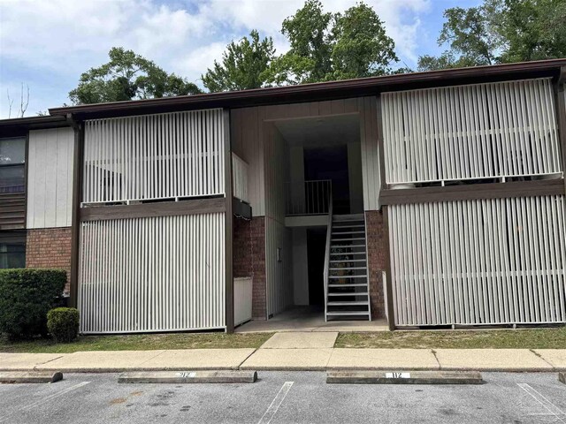 view of property with stairs and uncovered parking