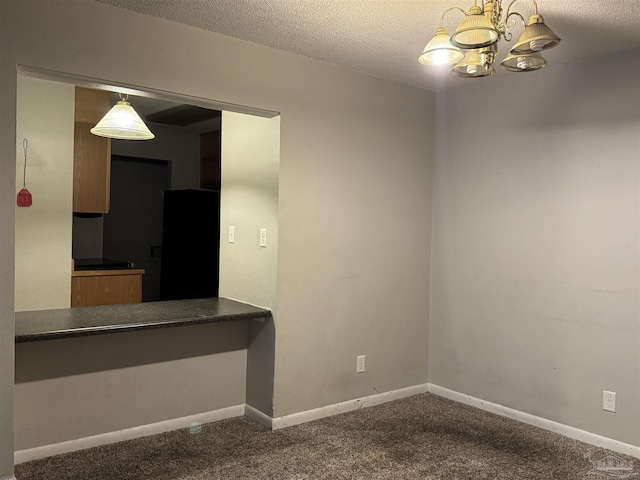 kitchen featuring dark countertops, freestanding refrigerator, dark colored carpet, and a chandelier