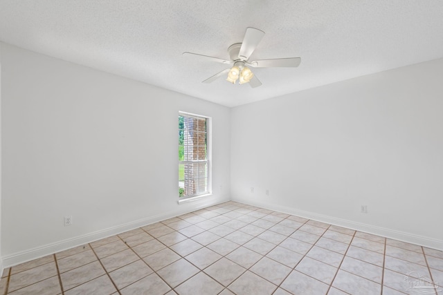 unfurnished room with ceiling fan, light tile patterned floors, and a textured ceiling