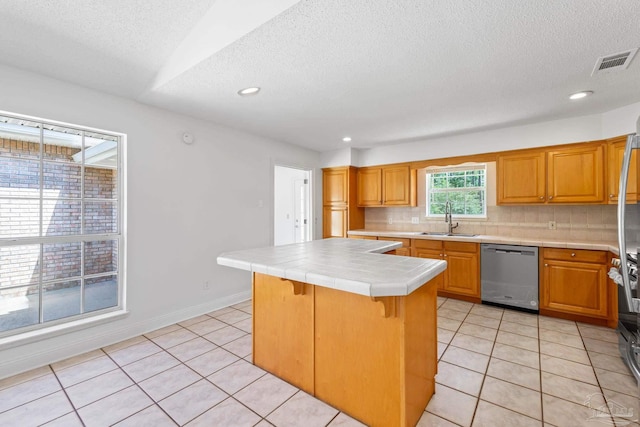 kitchen with stainless steel dishwasher, sink, tile countertops, a center island, and a breakfast bar area