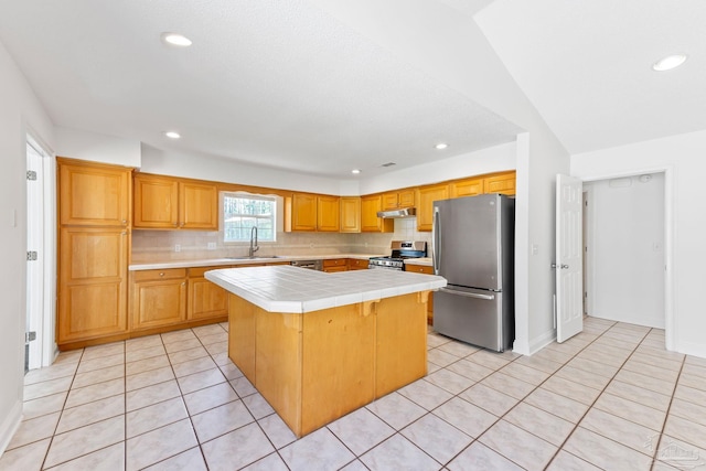 kitchen featuring appliances with stainless steel finishes, sink, a center island, tile counters, and light tile patterned flooring