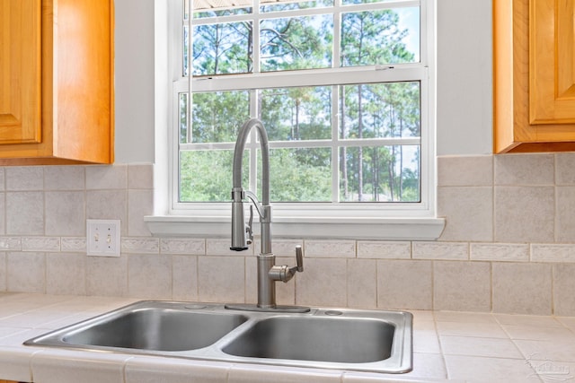 kitchen with tile counters, sink, a wealth of natural light, and tasteful backsplash