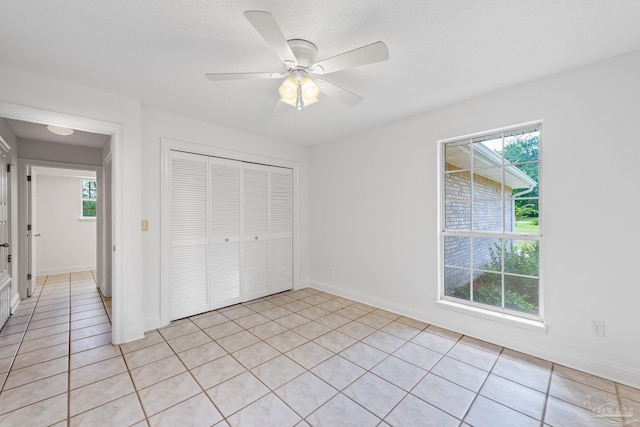 unfurnished bedroom with ceiling fan, a closet, and light tile patterned floors