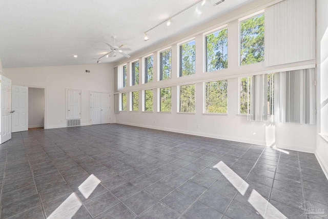 spare room with track lighting, high vaulted ceiling, dark tile patterned floors, and ceiling fan