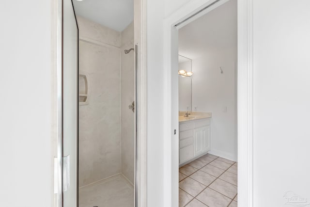 bathroom featuring a tile shower, tile patterned flooring, and vanity