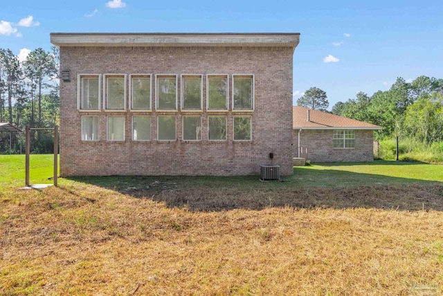 rear view of house with a lawn and central AC