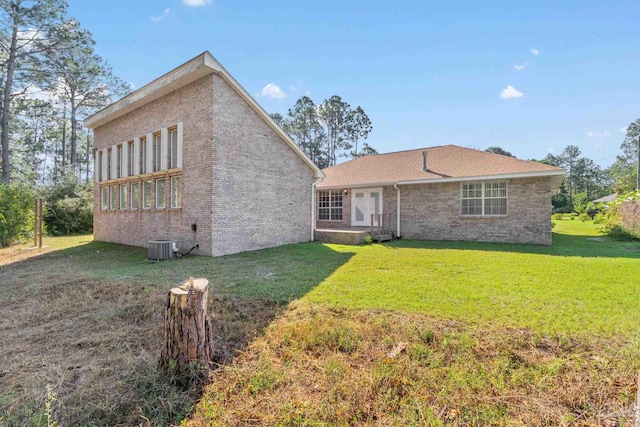 rear view of property featuring a yard and cooling unit