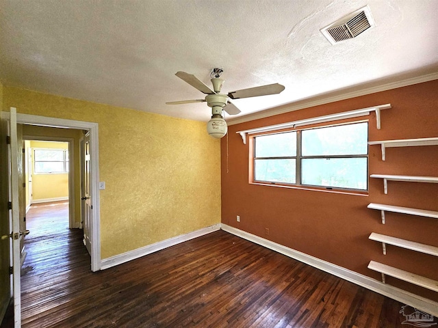 empty room with ceiling fan, ornamental molding, dark wood-type flooring, and a textured ceiling