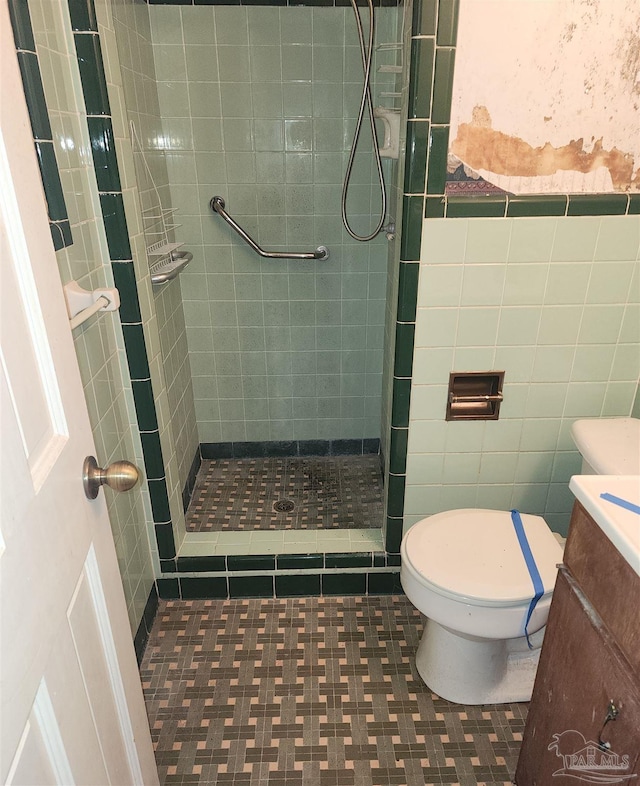 bathroom featuring tiled shower, vanity, toilet, and tile walls