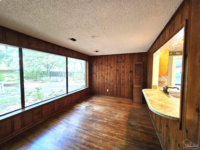 interior space featuring dark hardwood / wood-style floors, sink, a textured ceiling, and wood walls