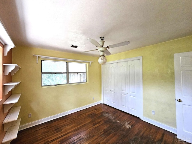 unfurnished bedroom with dark wood-type flooring, ceiling fan, and a closet