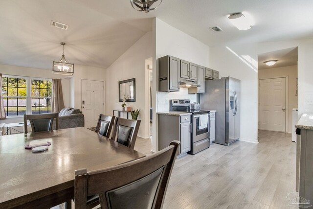 dining area with light wood finished floors, visible vents, vaulted ceiling, and a chandelier