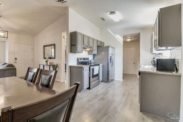 kitchen featuring lofted ceiling, light wood-style flooring, appliances with stainless steel finishes, and tasteful backsplash