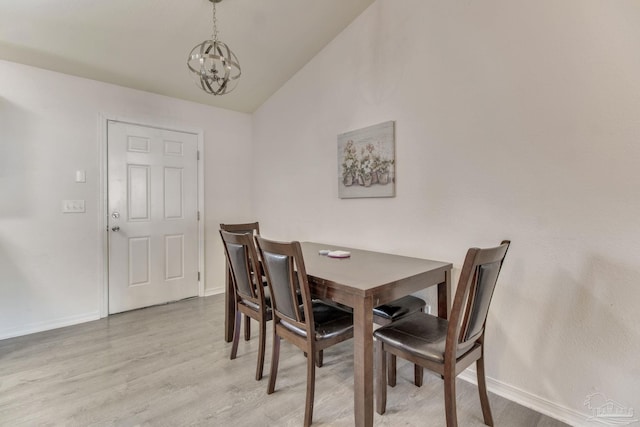 dining room with lofted ceiling, light wood finished floors, baseboards, and a notable chandelier